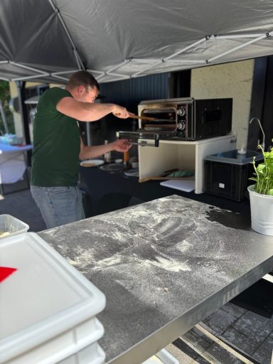 Ein Mann bereitet Essen in einem mobilen Küchenstand unter einem Zeltdach vor.