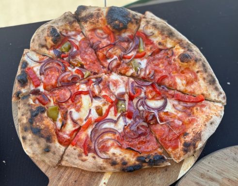 Steinofenpizza mit Tomatensauce, Zwiebeln, Paprika und Salami.