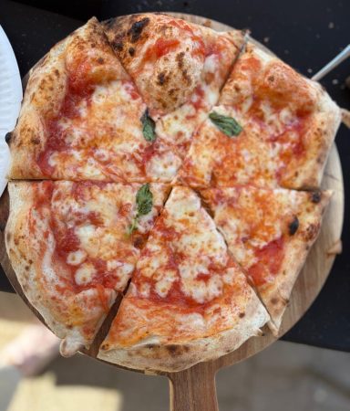 Pizza Margherita auf Holzbrett, mit Käse, Tomatensauce und frischem Basilikum.