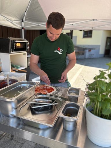 Ein Mann bereitet Essen an einem Marktstand unter einem Pavillon vor.