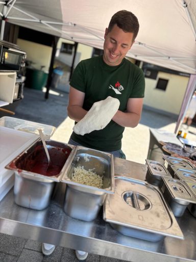 Ein Verkäufer in grüner T-Shirt, der Essen aus Edelstahlbehältern vorbereitet.